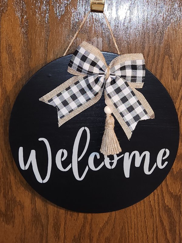 Gray "Welcome" door sign on black